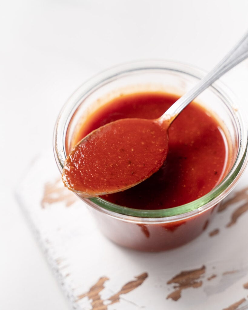 top view of a jar with bbq sauce and a spoonful over the jar