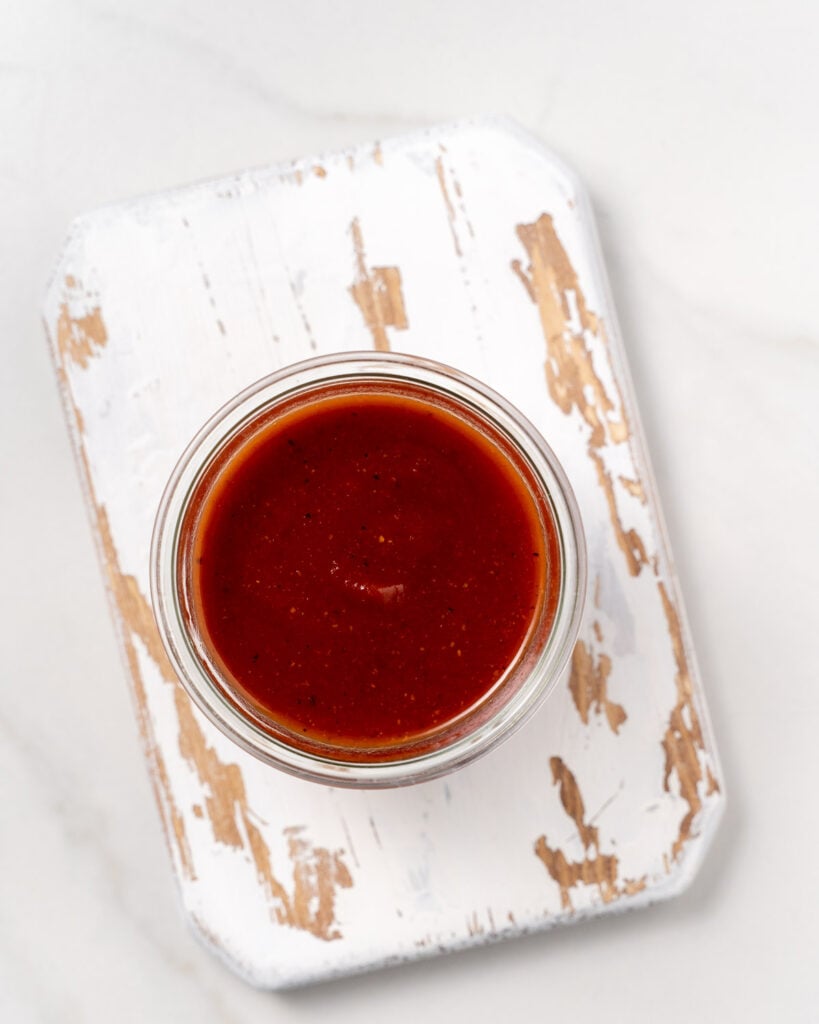top view of a jar with homemade BBQ sauce over a wooden board 
