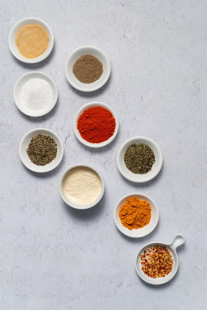 garlic powder, oregano, thyme, cayenne pepper, salt, black pepper, paprika in bowls