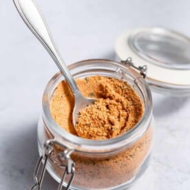 side shot of cajun seasoning in a jar with spoon in it