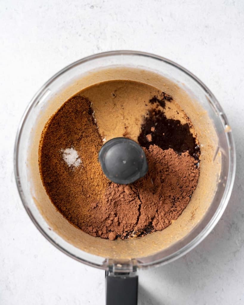 cocoa powder and sugar added into blended hazelnuts in a food processor
