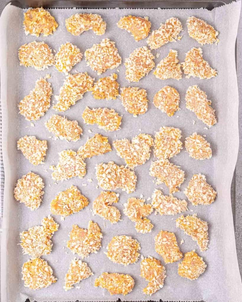 Chicken pieces on a parchment lined baking sheet.
