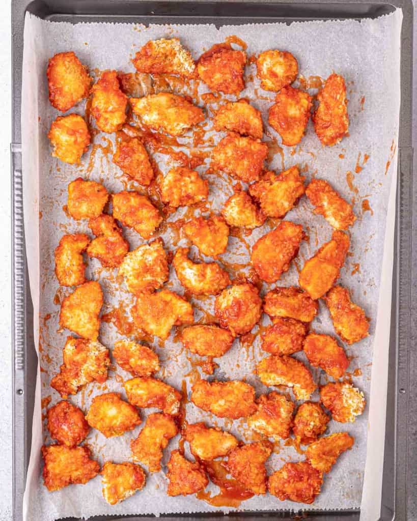 Sauce drizzled over chicken pieces on a baking sheet pan.