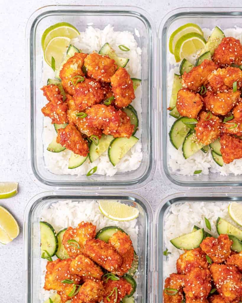 Glass containers filled with rice, chicken and cucumbers.
