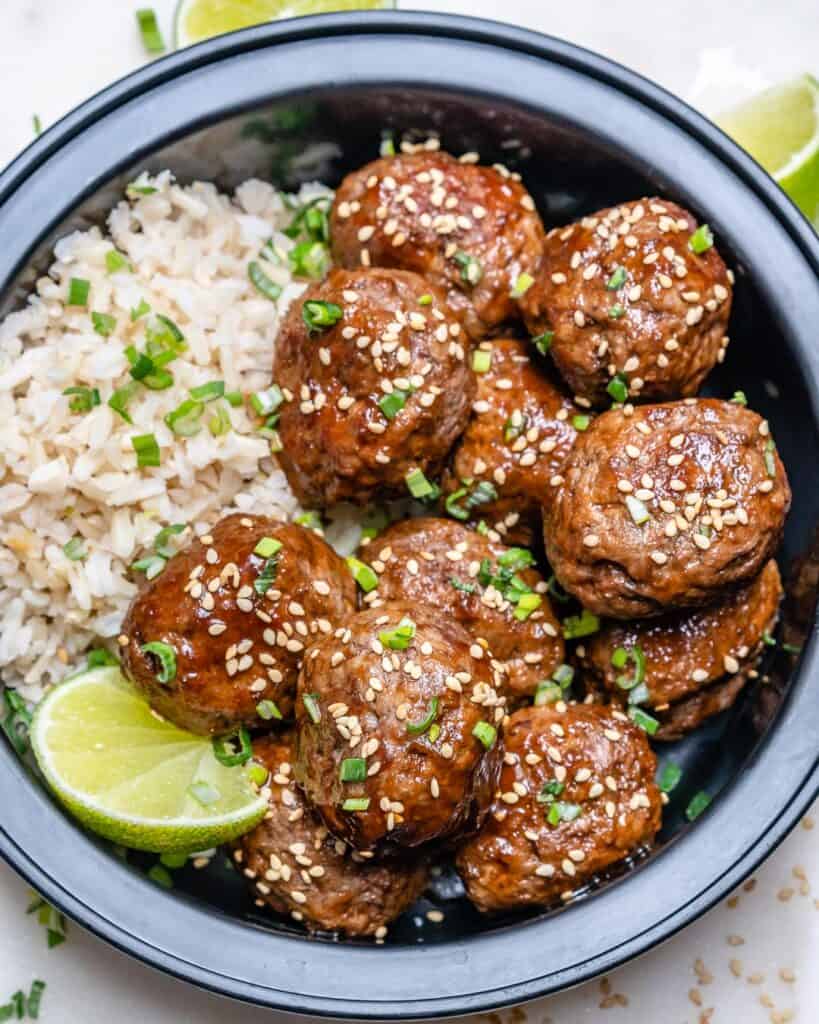 top view of a black meal prep bowl with meatballs and rice