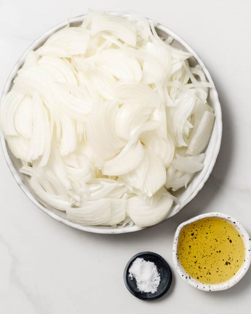 ingredients for making caramelized onions. a plate of sliced onions, salt, and olive oil