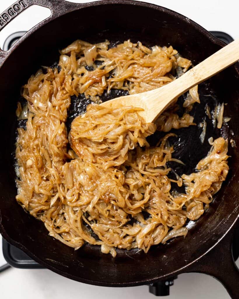 caramelized onions being mixed in a black skillet