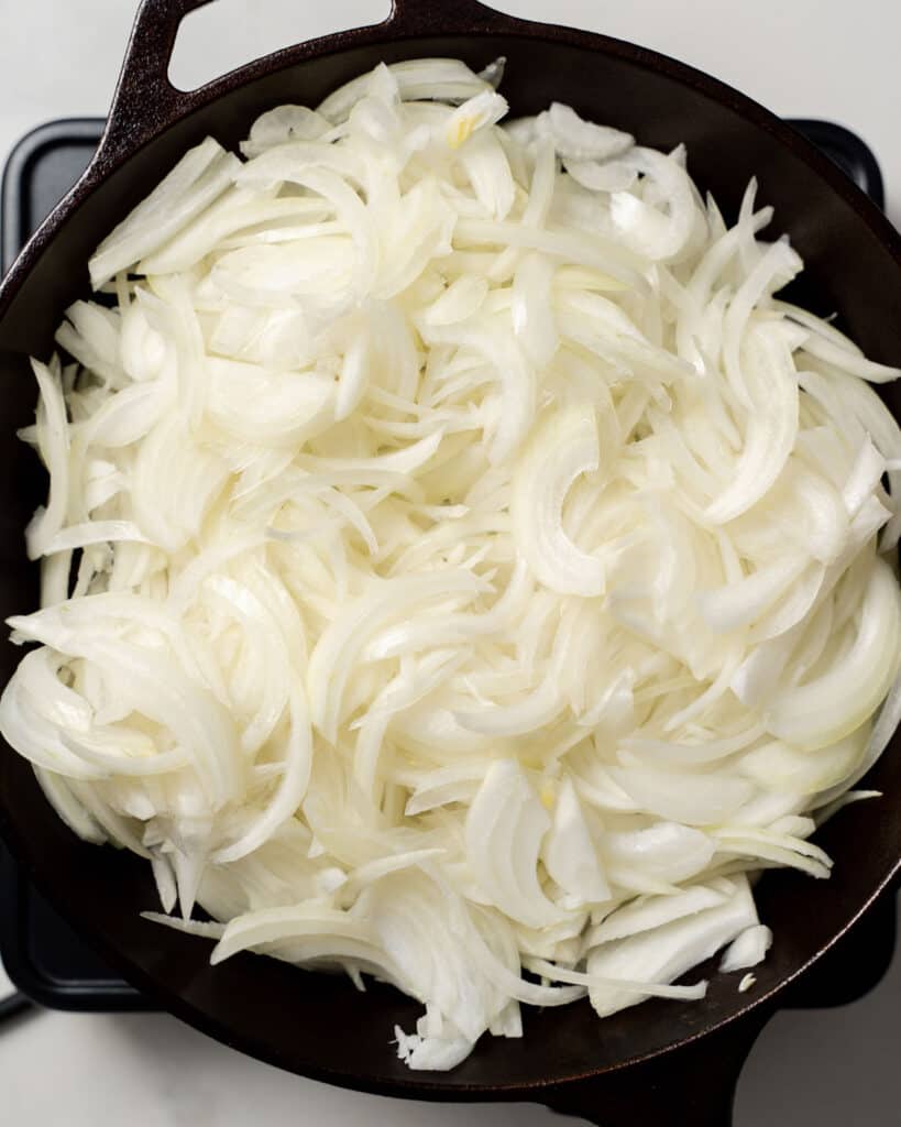 sliced raw onions added in a black skillet