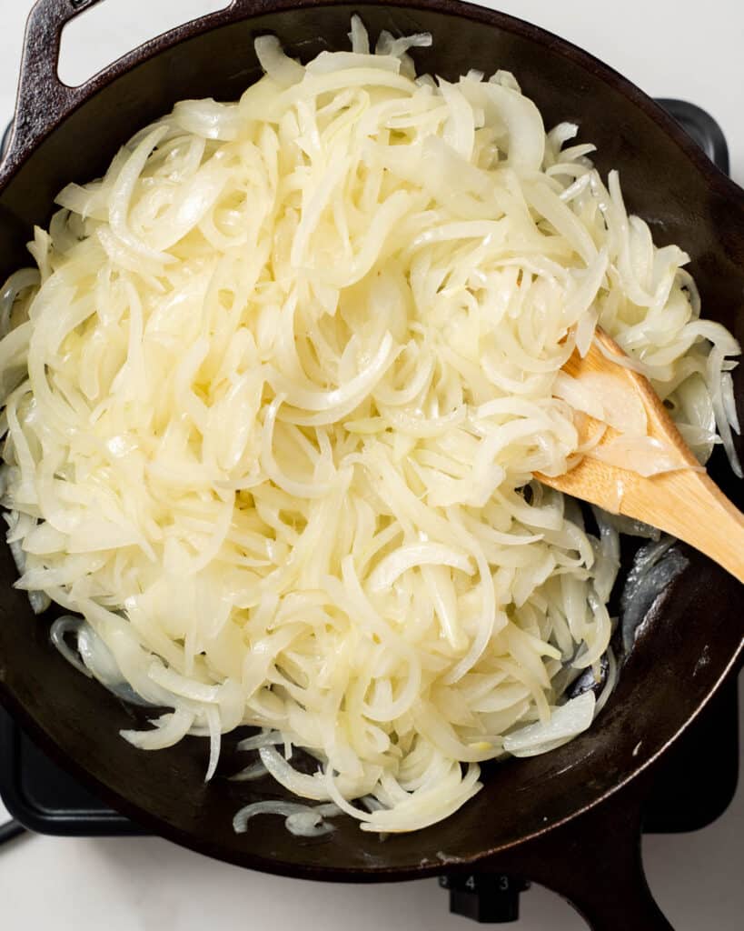 onions starting to saute in pan with a wooden spoon