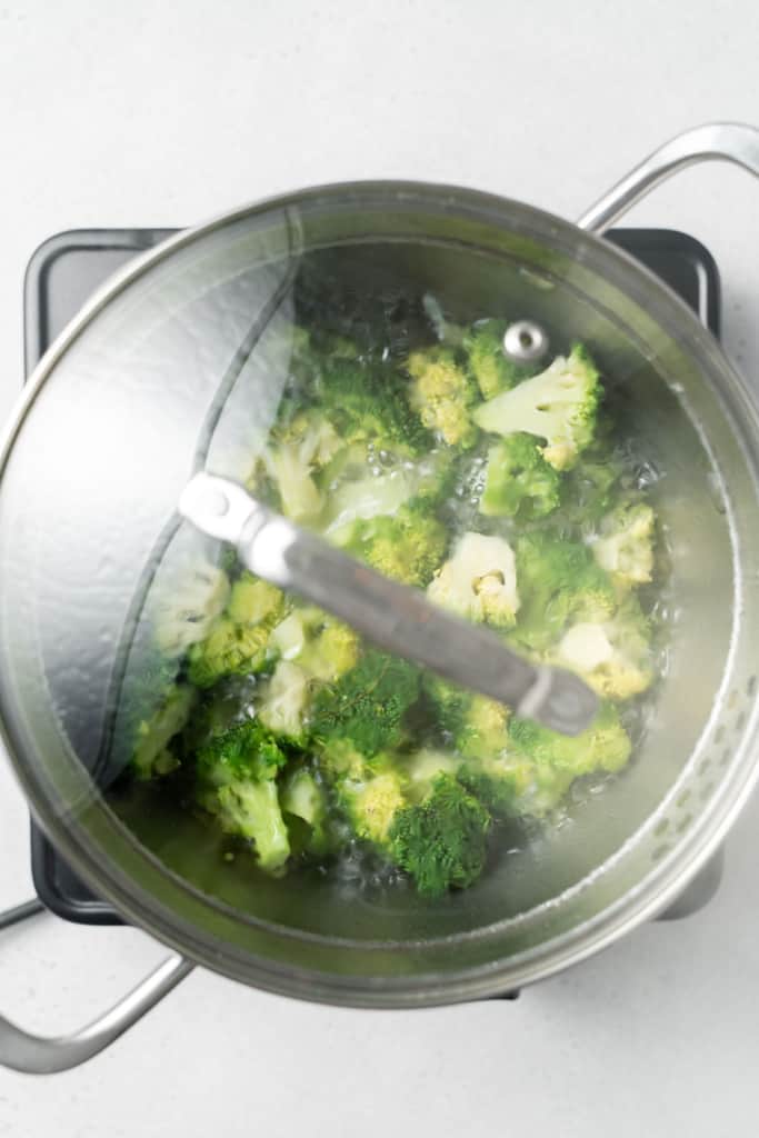 Boiling broccoli in a covered pot.
