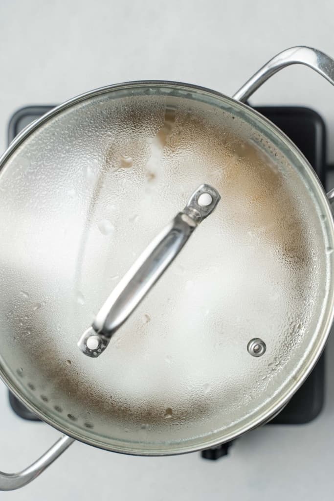 Cooking chickpeas with a lid on a pot.