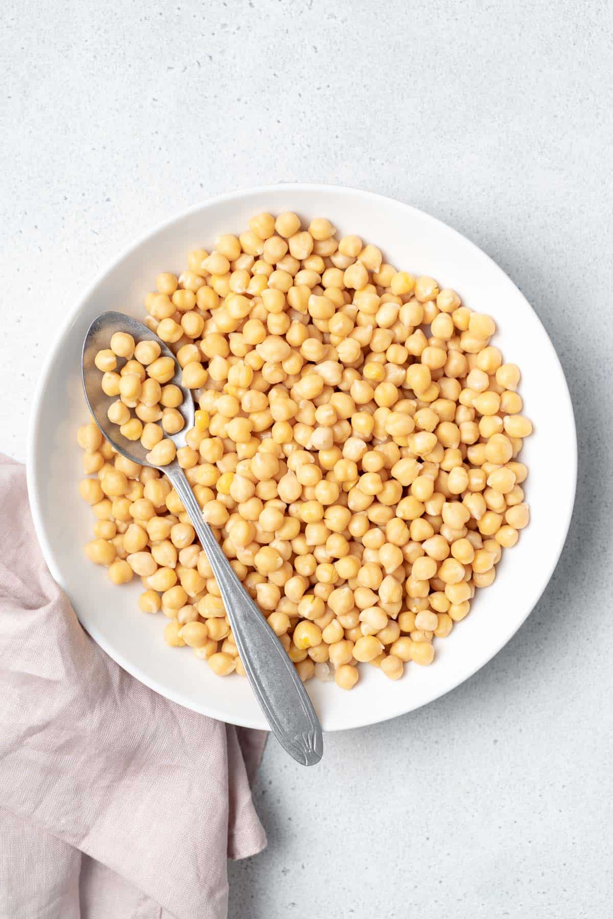 Spoon on a white bowl filled with chickpeas.