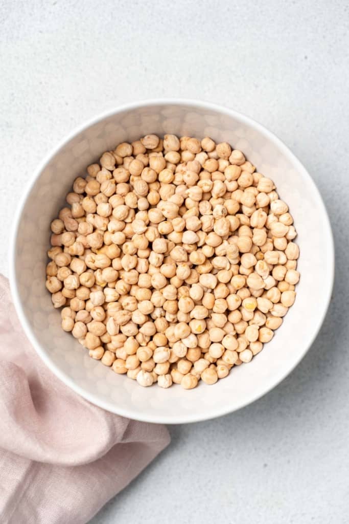Uncooked chickpeas in a white bowl.