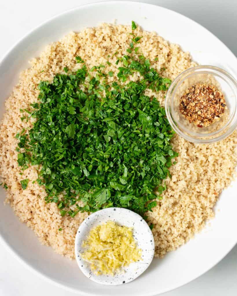 Cooked couscous, chopped fresh parsley, garlic and lemon zest in small bowls.