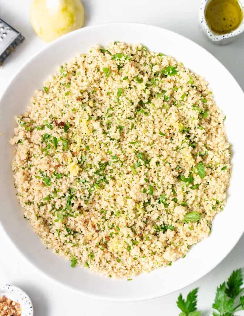 top view of round white plate with cooked couscous topped with fresh parsley
