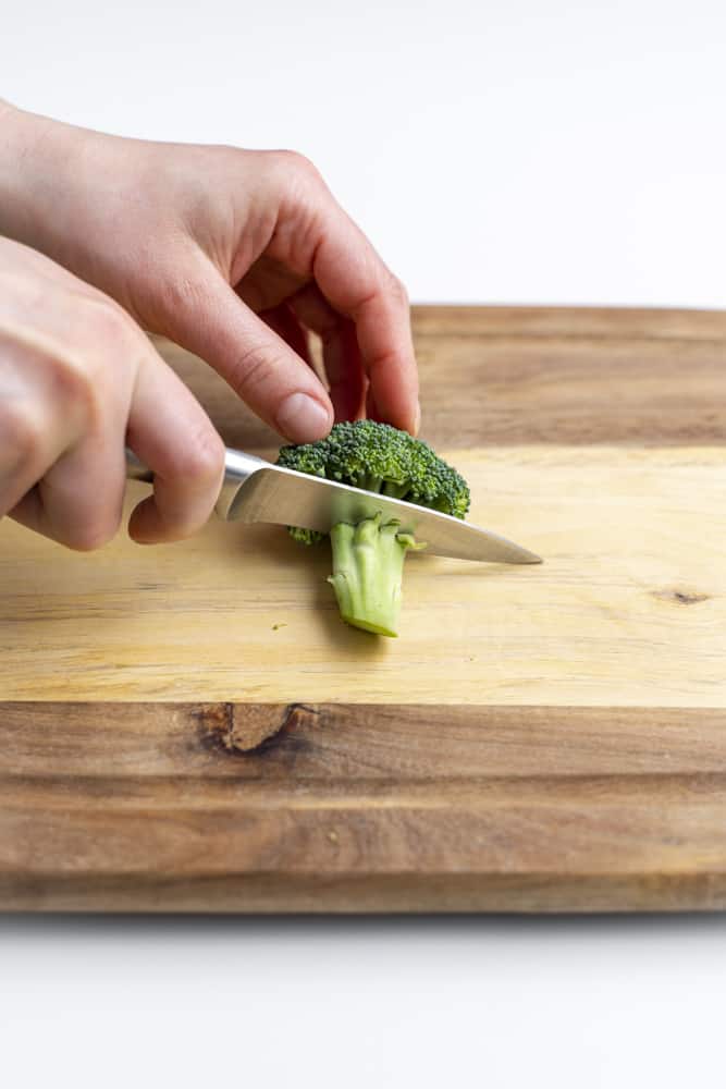 Cutting the stem off of a floret of broccoli.