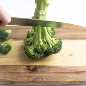 Knife cutting over broccoli stem.