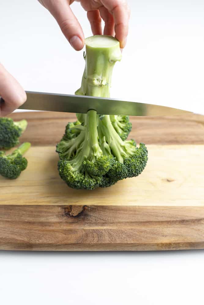Knife cutting over broccoli stem.