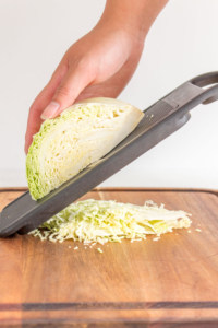 cabbage being shredded using a mandolin