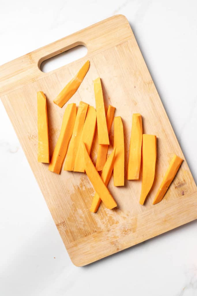 Long sticks of a sweet potato on a cutting board.