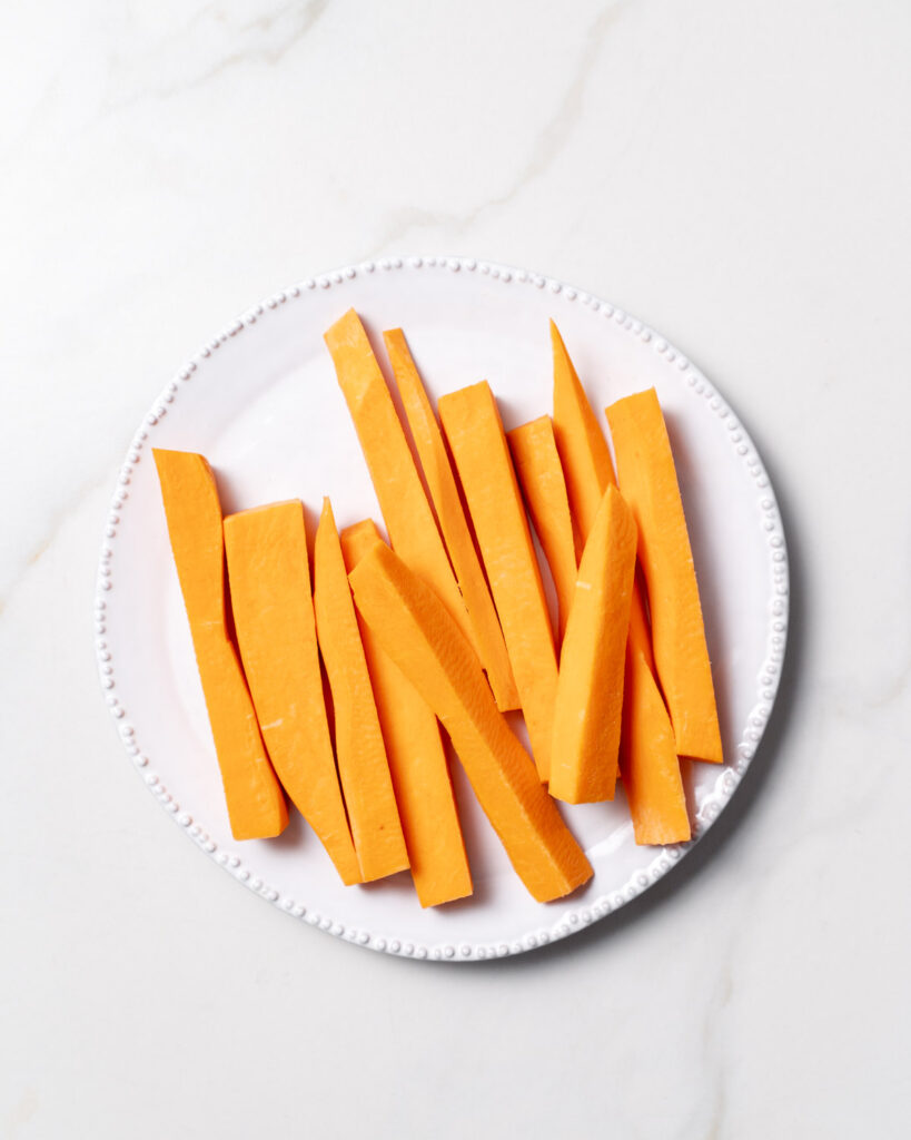 Sweet potatoes cut into sticks on a white plate.