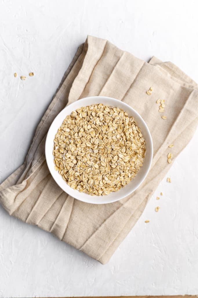 White bowl with rolled oats on a cloth napkin.