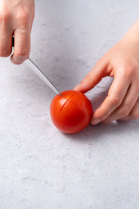 cutting an X in bottom of tomato with knife