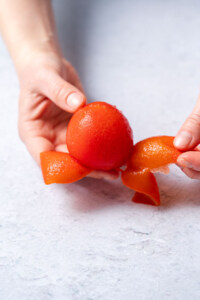 peeling a tomato with hands