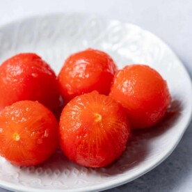 image of 5 peeled tomatoes on a white plate