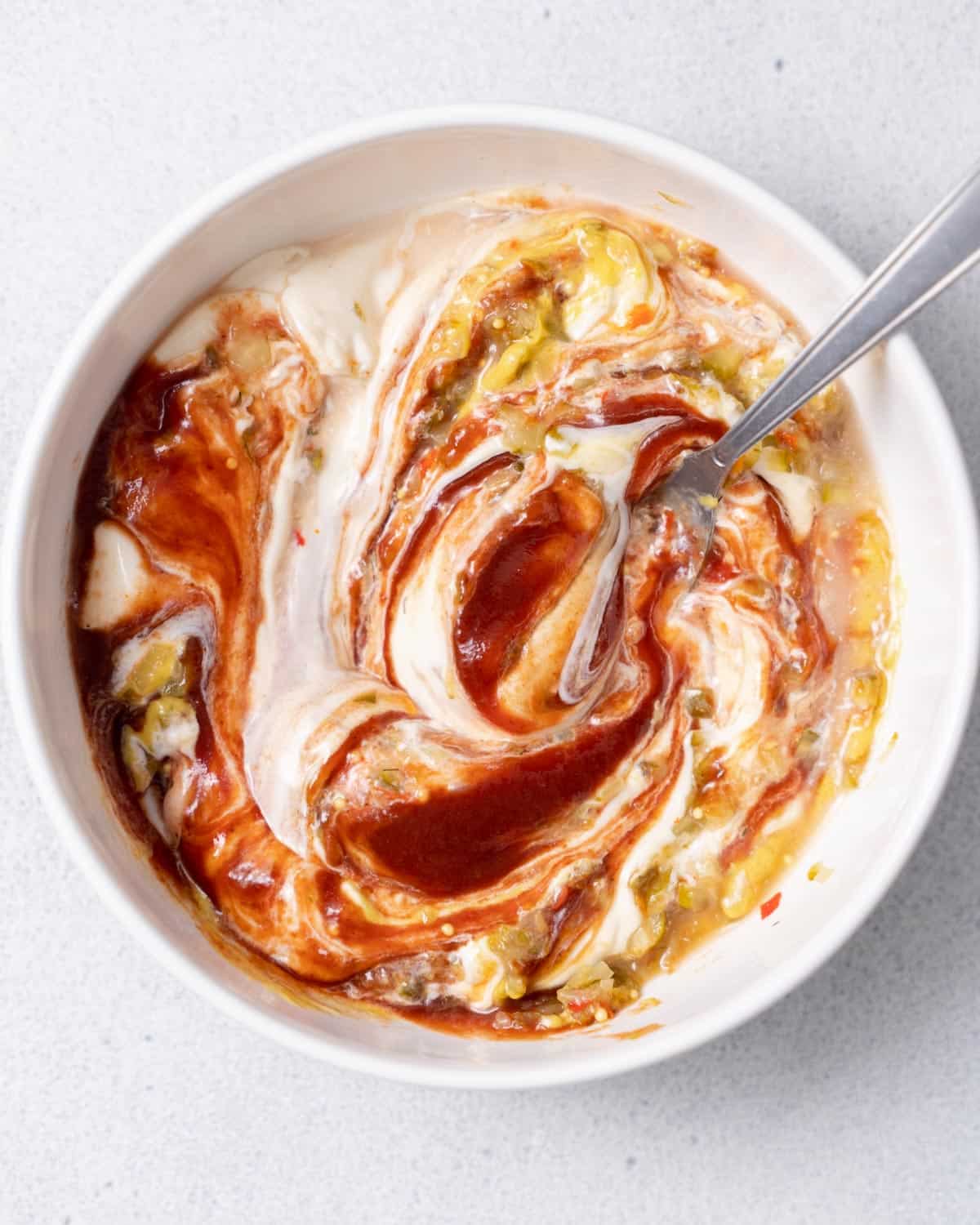 Stirring together mayo with ketchup and honey in a white bowl.