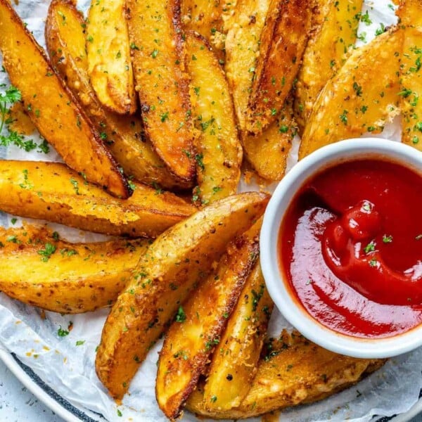 baked potato wedges with a side of ketchup in a small white bowl.