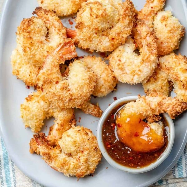 a dish with coconut shrimp next to a small bowl of dipping sauce