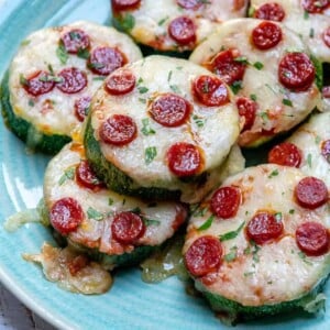 Zucchini pizza bites on a plate that is topped with mini pepperonis.
