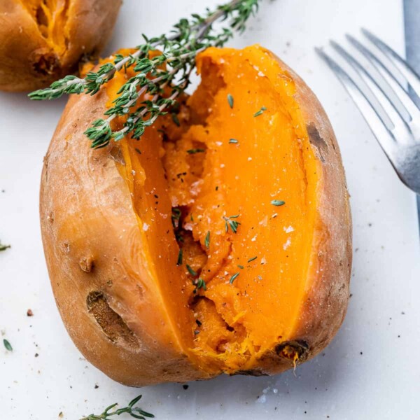 side shot of sweet potato sliced in half on a white platter