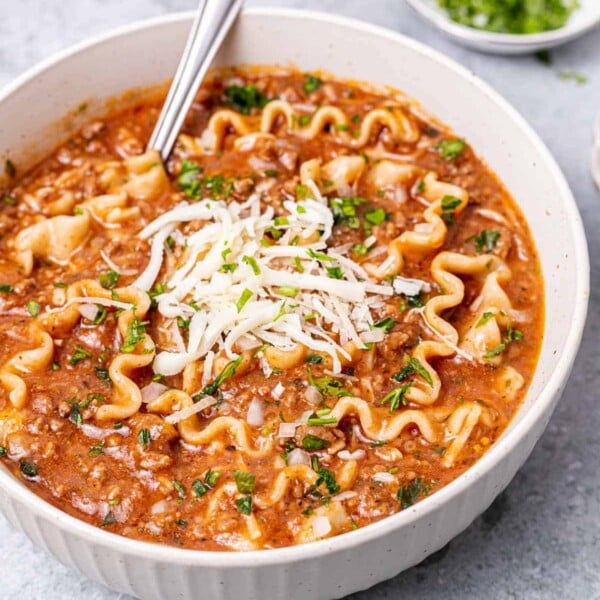 side shot of lasagna soup in a white bowl with spoon in it
