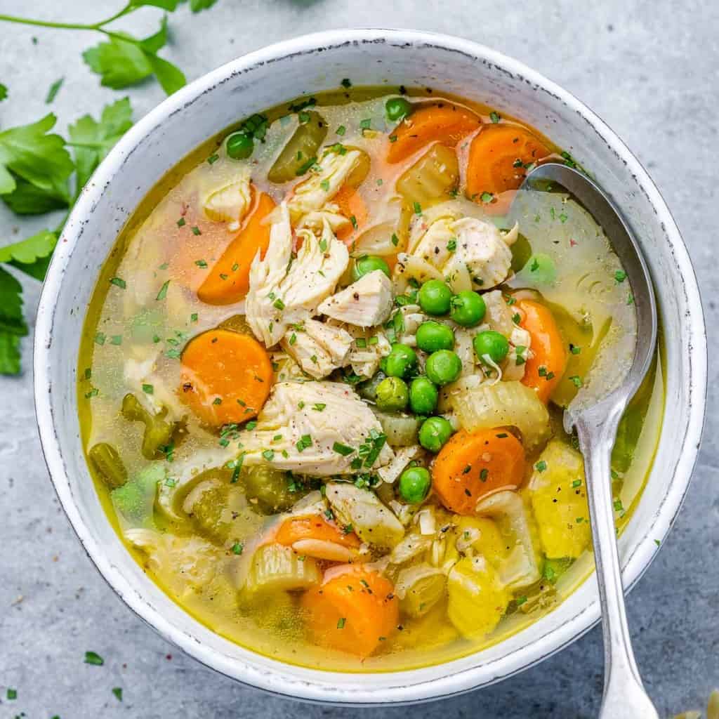 top view turkey soup with veggies in a white bowl