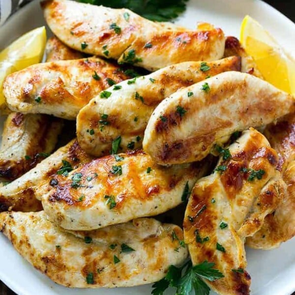 lemon garlic marinated chicken tenders on a wite plate topped with fresh chopped parsley