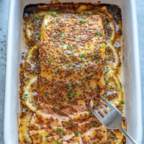 baked salmon in white dish with fork flaking it