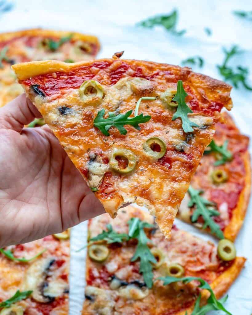 hand holing a slice of pizza with a bute taken off the lice 