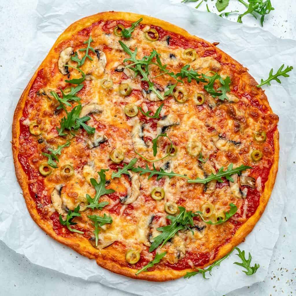 top view of a baked thin-crust pizza topped with cheese and sliced green olives