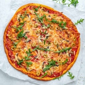 top view of a baked thin-crust pizza topped with cheese and sliced green olives