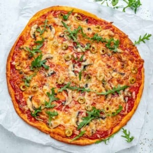 top view of a baked thin-crust pizza topped with cheese and sliced green olives