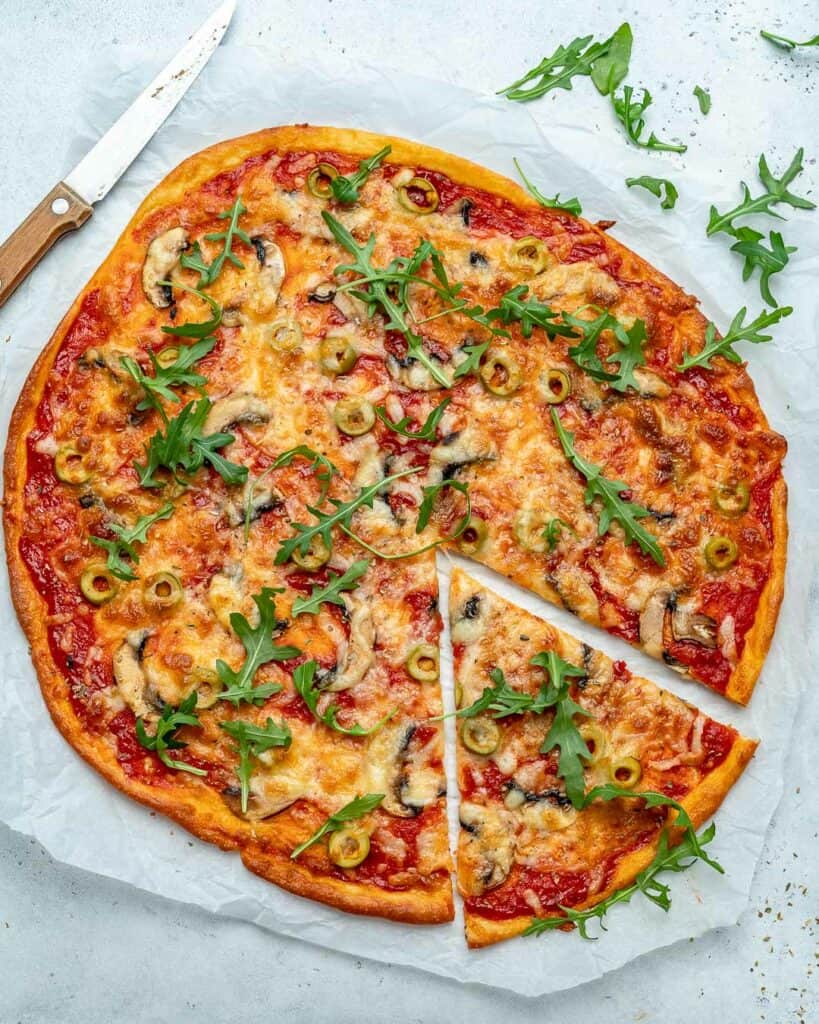 top view of a round pizza on a parchment paper with one slice cut out