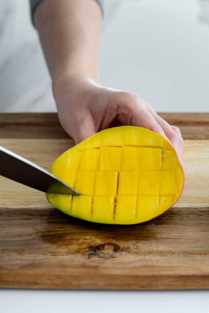 knife slicing cubes in mango flesh