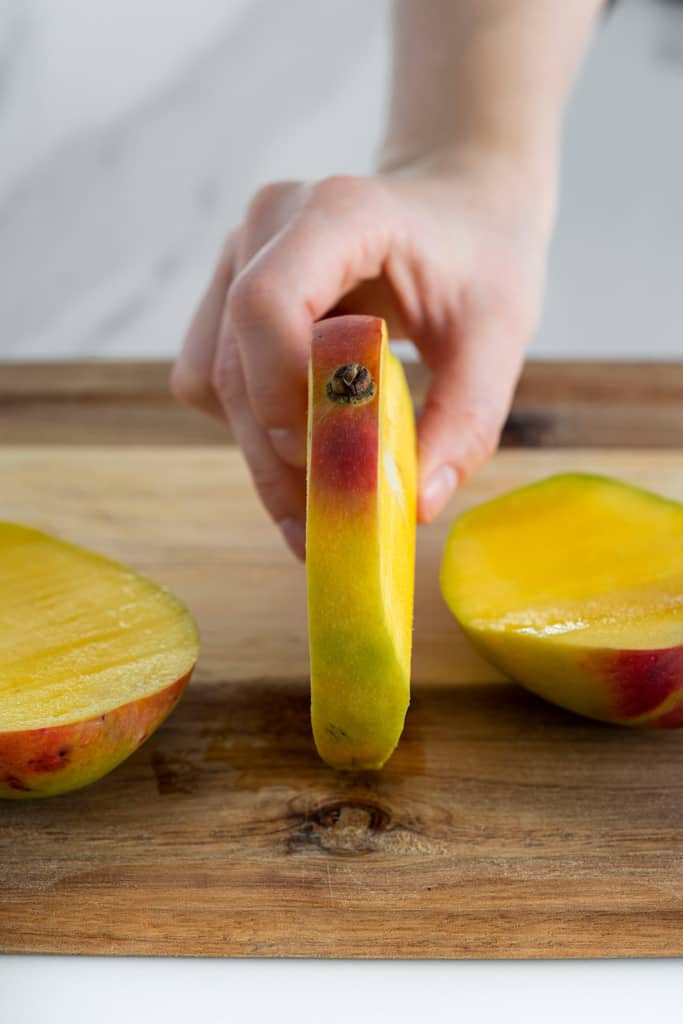hand holding mango seed stem side up 