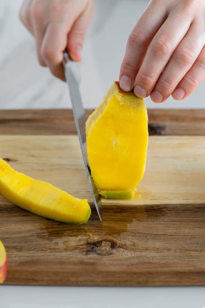 side shot of mango flesh being cut from mango
