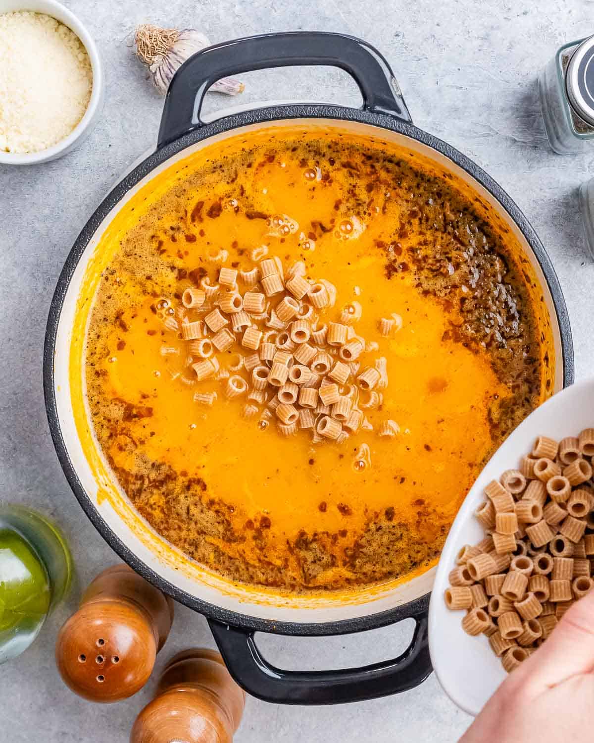 Pouring pasta into a pot of soup.