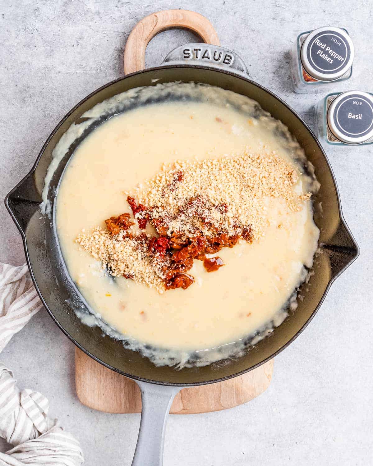 creamy sauce in a black skillet with sun-dried tomatoes.