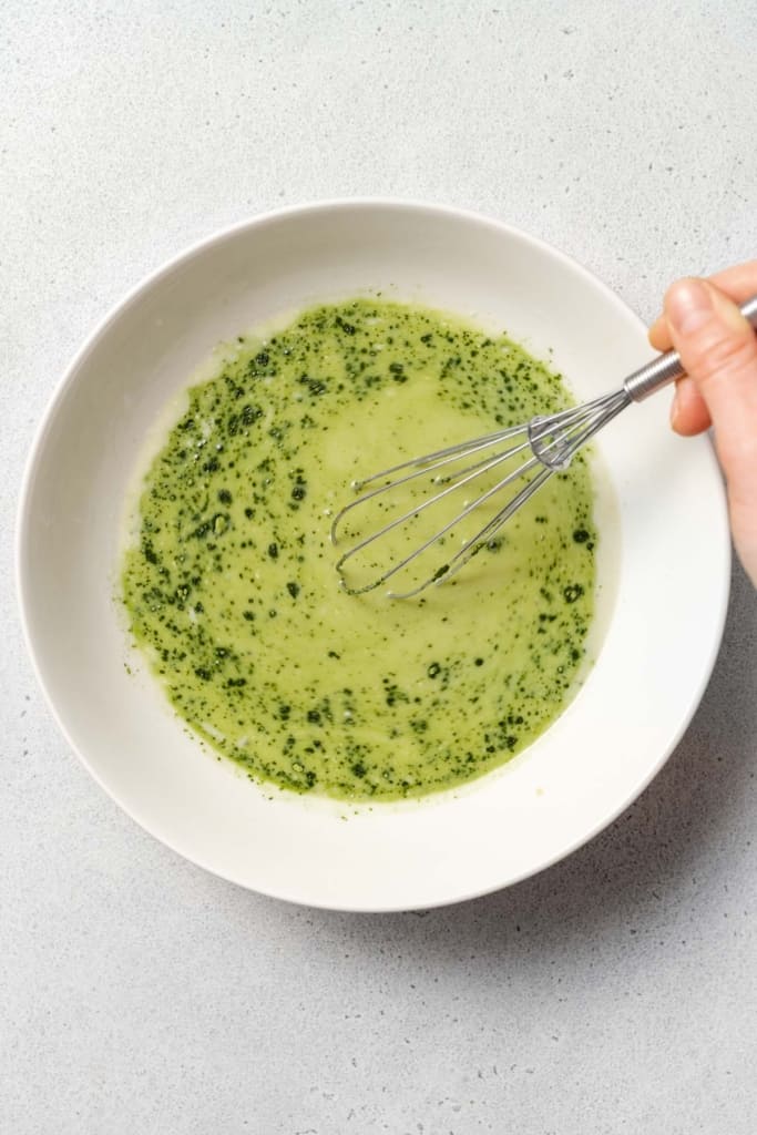 hand with whisk mixing milk