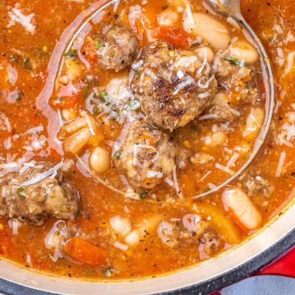 Ladel scooping meatball and bean soup.